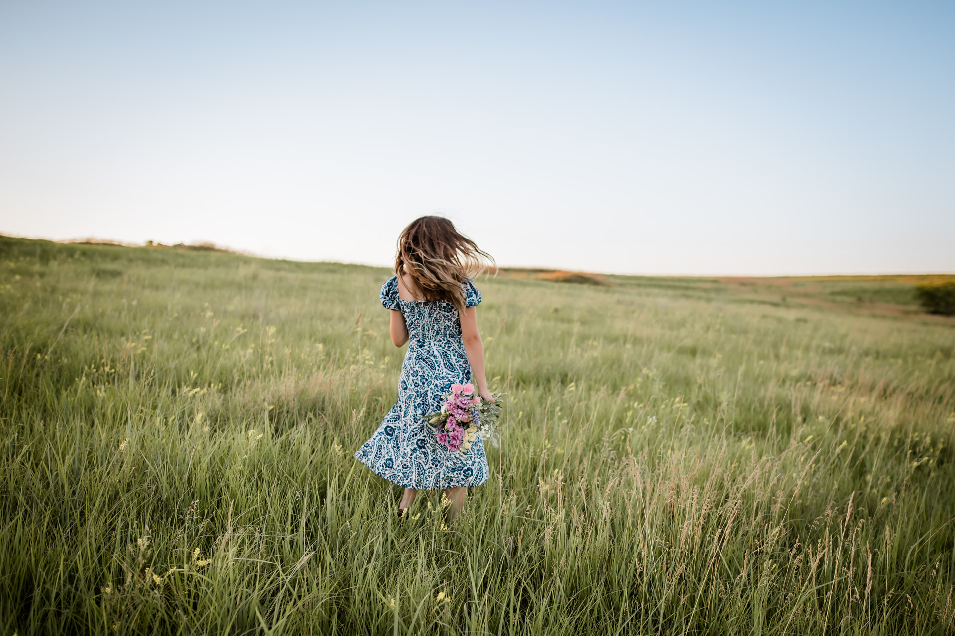 Girl running through golden field at sunset