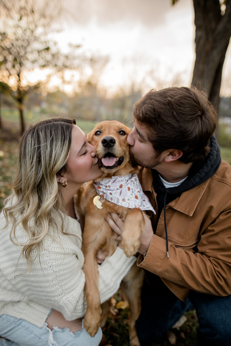 Couple and their dog at golden hour in a grassy field